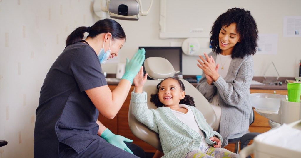 Child, high five and dentist for consultation with discussion, oral hygiene and mouth cleaning service. Mother, health professional and orthodontic inspection for dental care with girl for checkup.